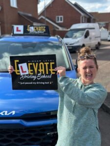 Beginner driving lessons success: happy female student with driving instructor.